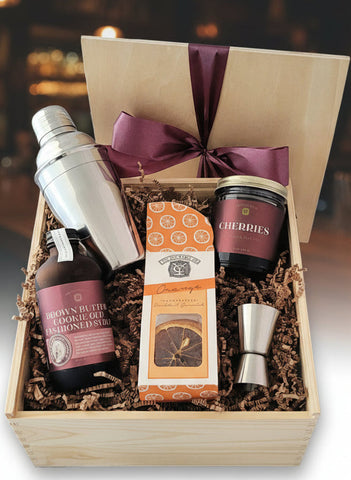 Gift set with cocktail shaker, bottles, and packaging in a wooden box.
